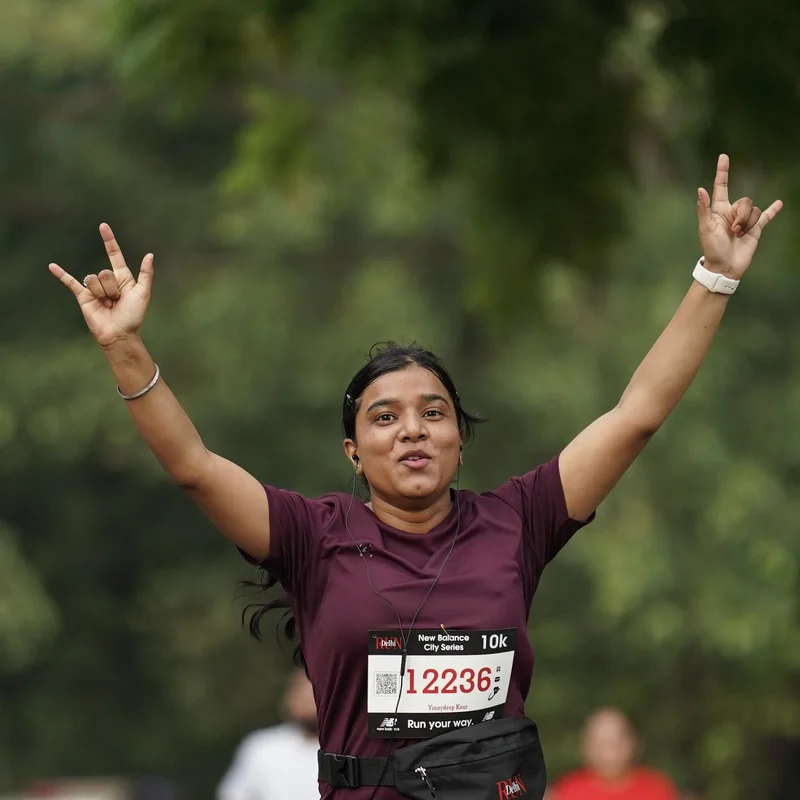 Vinaydeep running a 10K in Delhi with both arms raised, smiling