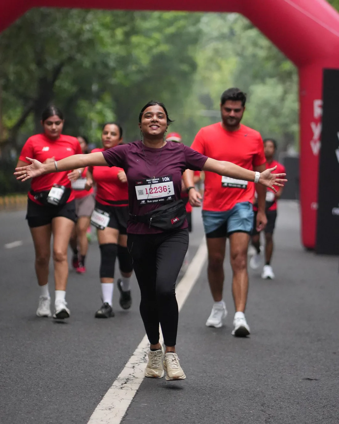 Vinaydeep crossing a 10K finish arch with arms wide open